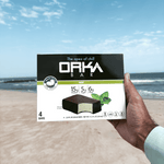 Hand holding a box of Orka Bar on a beach with ocean view