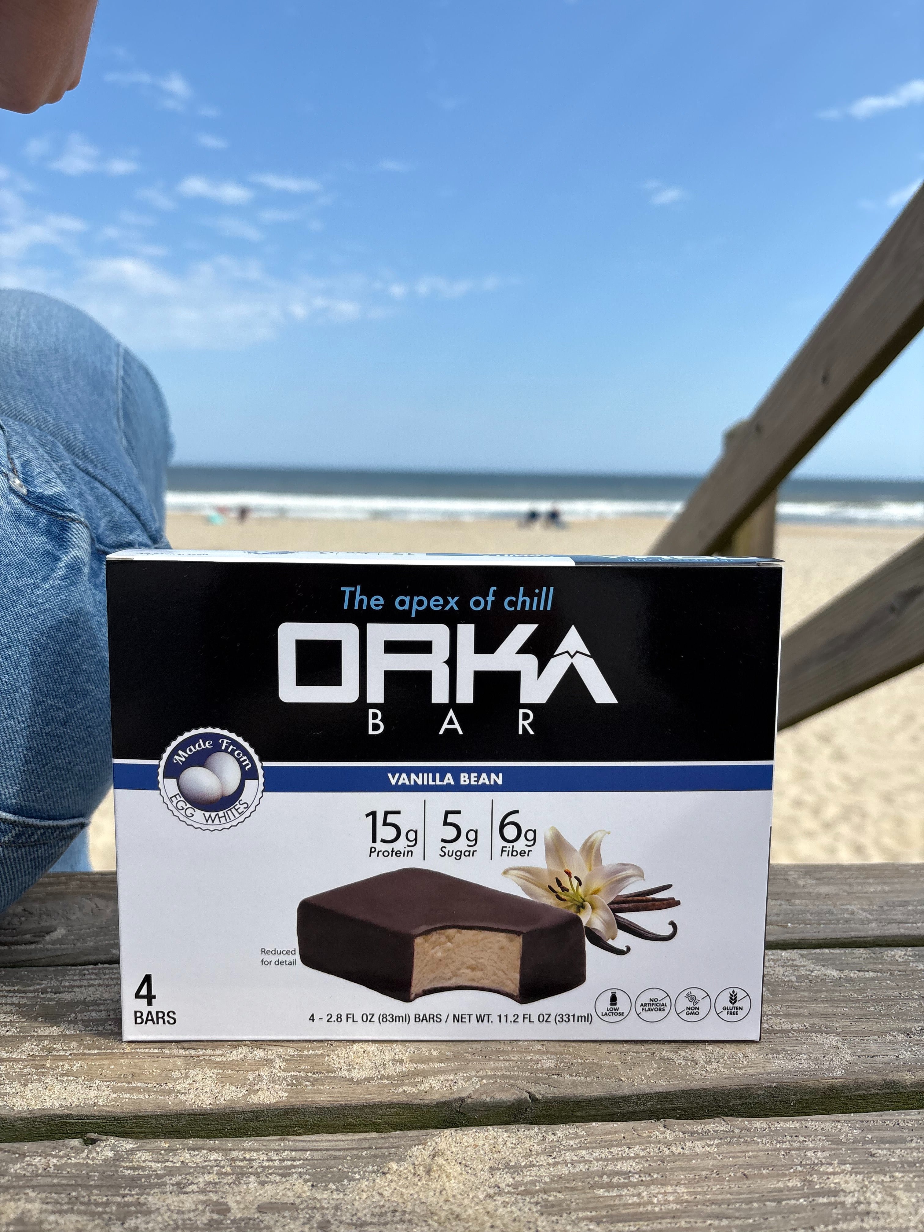Box of Orka Bar on a wooden surface with a beach in the background