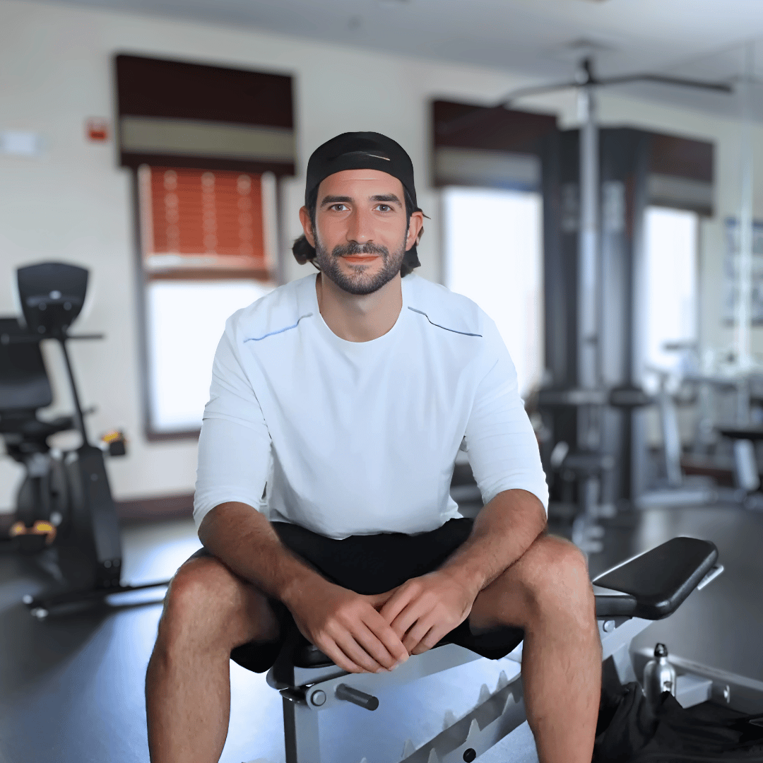Stephen sitting on a weight bench in a gym